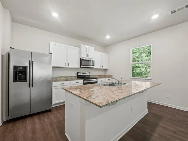 a kitchen with kitchen island granite countertop a sink cabinets and stainless steel appliances