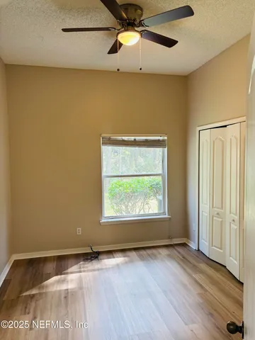 an empty room with wooden floor fan and windows