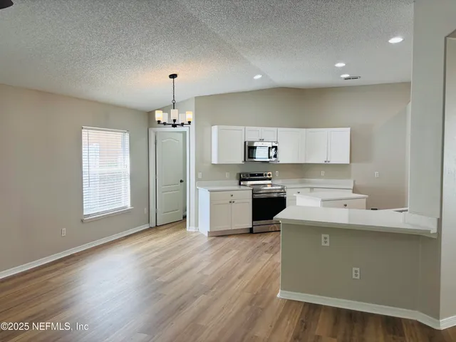 a kitchen that has a lot of cabinets in it and wooden floors