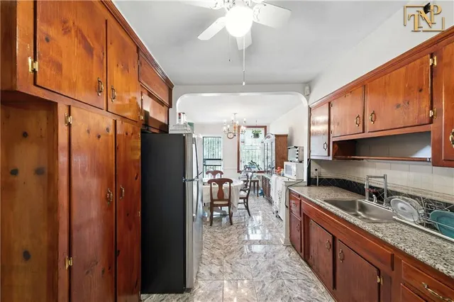 a kitchen with granite countertop a refrigerator a sink a stove and cabinets