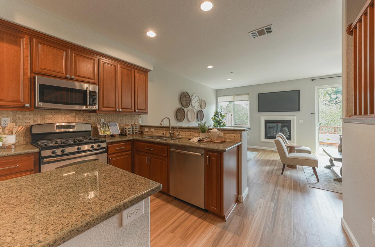 145 Atherton Loop Aptos, CA 95003 - Photo 12 of 47 a kitchen with granite countertop a stove top oven a sink dishwasher a dining table and chairs with wooden floor