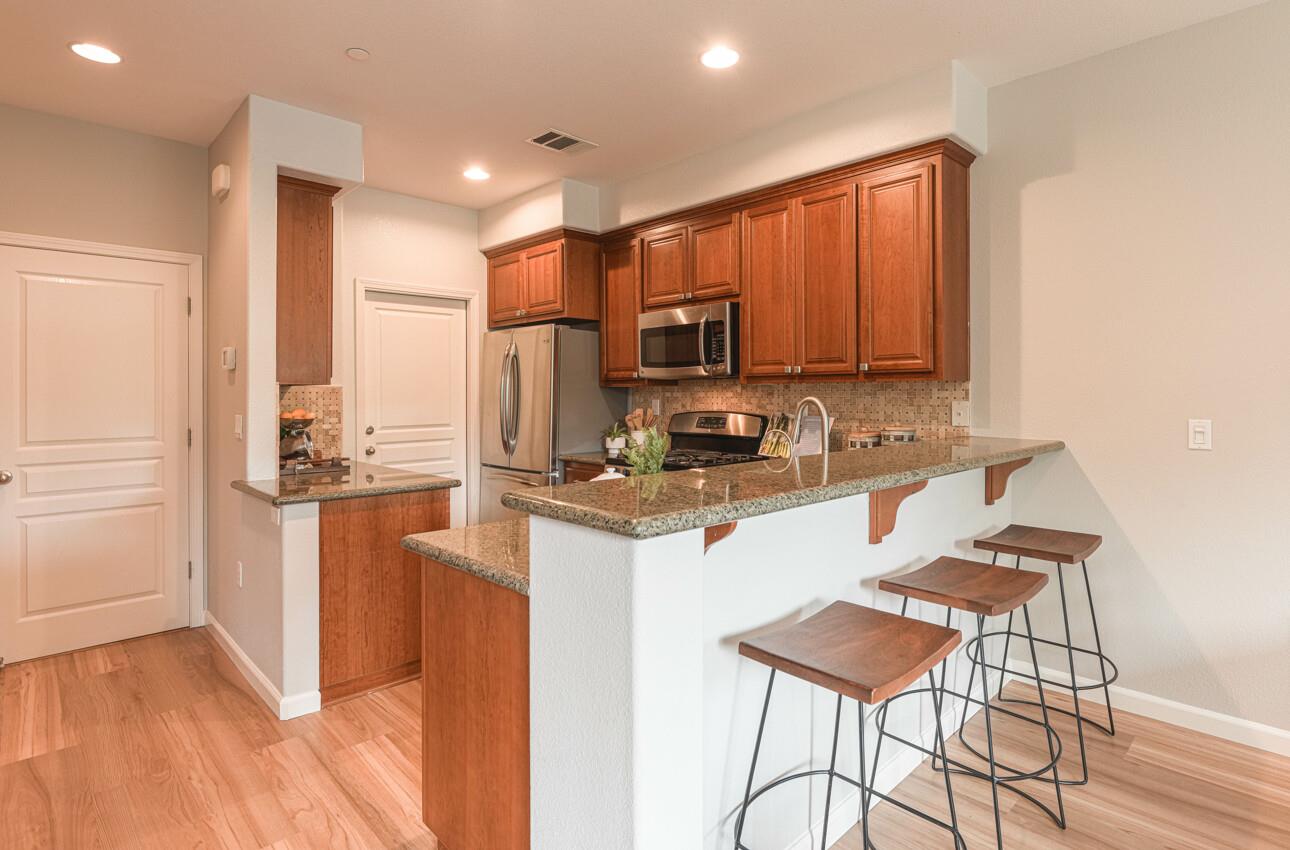 145 Atherton Loop Aptos, CA 95003 - Photo 15 of 47 a kitchen with stainless steel appliances granite countertop a stove a refrigerator a sink a dining table and chairs with wooden floor