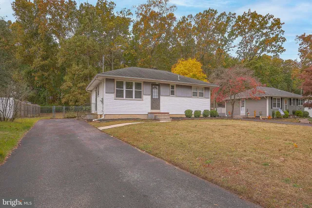 a front view of house with yard and trees in the background