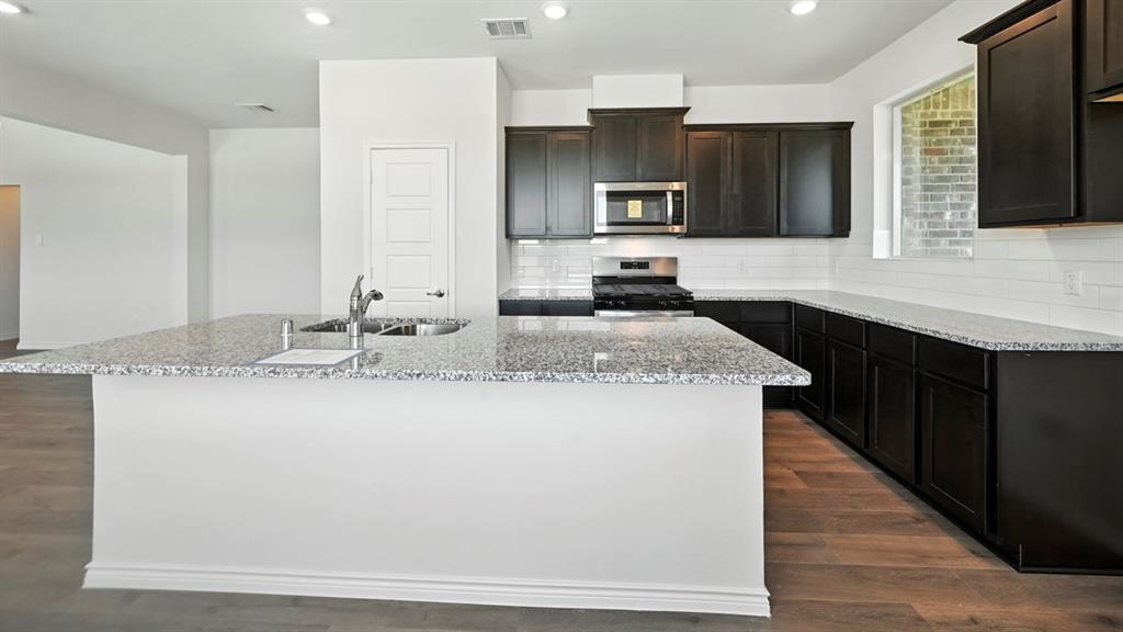 2345 Chloe Lane Anna, TX 75409 - Photo 25 of 36 a large kitchen with granite countertop a sink and a stove top oven