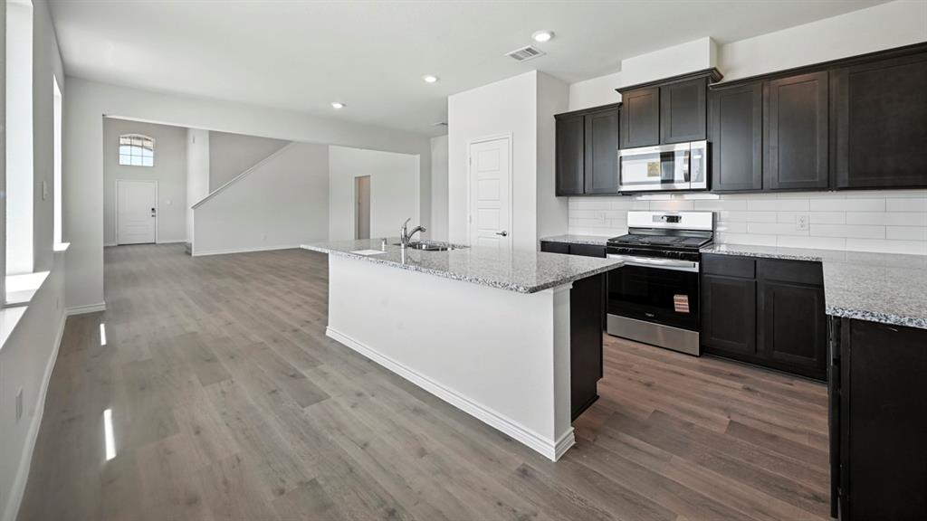 2345 Chloe Lane Anna, TX 75409 - Photo 26 of 36 a kitchen with stainless steel appliances kitchen island granite countertop a stove a sink and a microwave