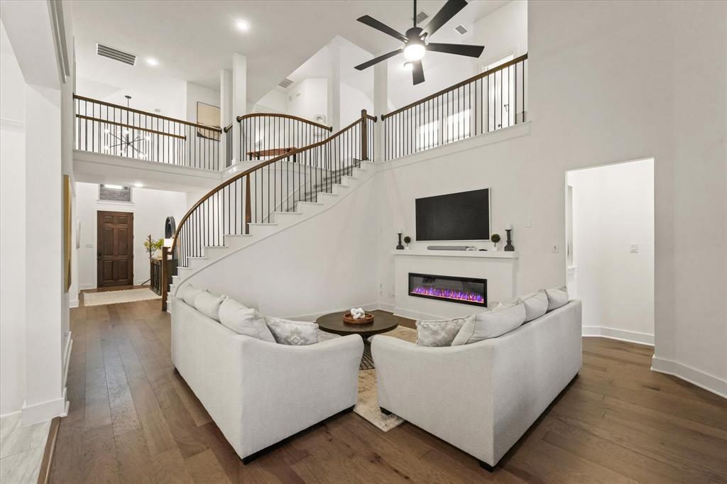 1714 Highwood Road Forney, TX 75126 - Photo 9 of 30 Soaring ceilings with a decorative ceiling fan, wood-finish flooring, and a contemporary fireplace with a mantel