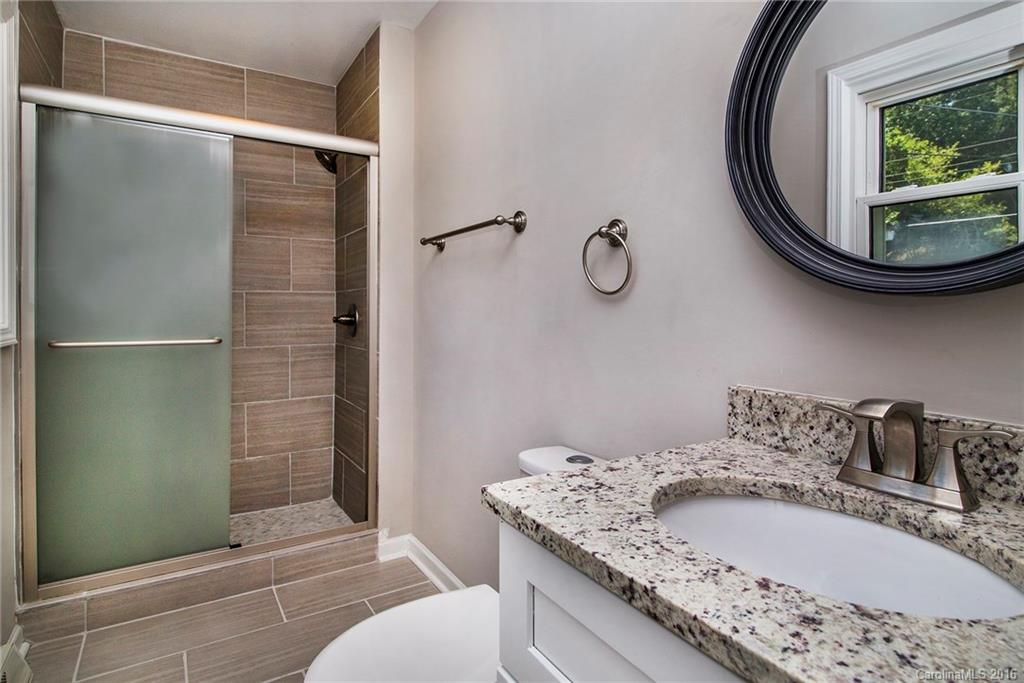 4209 Woodleaf Road Charlotte, NC 28205 - Photo 12 of 18 a bathroom with a granite countertop sink a mirror and shower