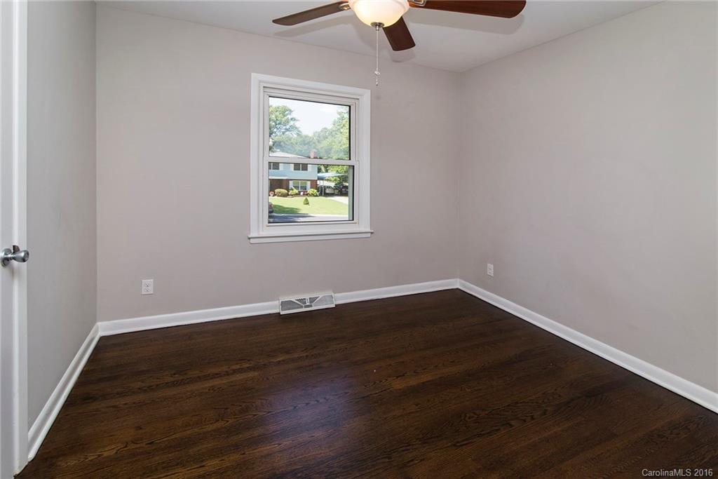 4209 Woodleaf Road Charlotte, NC 28205 - Photo 14 of 18 an empty room with wooden floor cabinet and windows