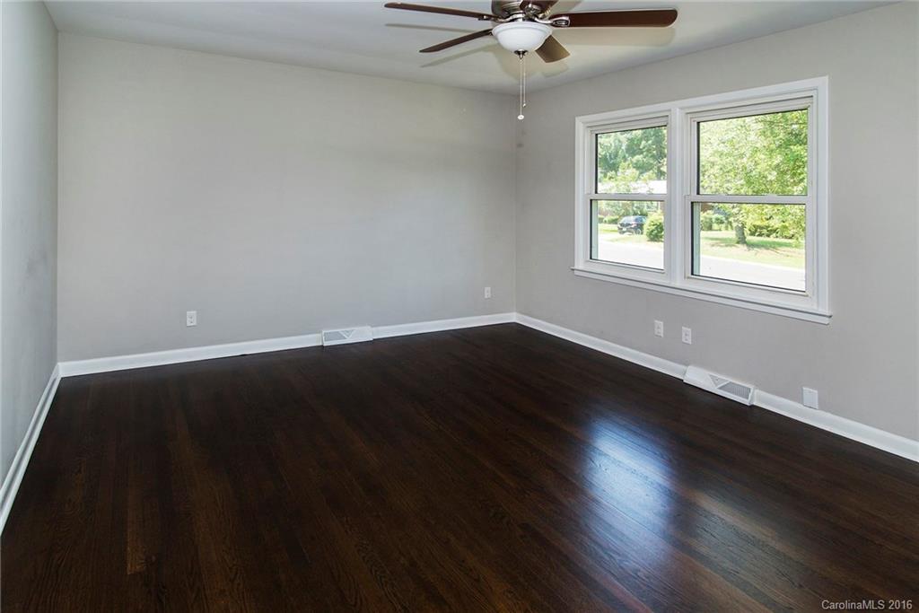 4209 Woodleaf Road Charlotte, NC 28205 - Photo 4 of 18 an empty room with wooden floor and windows