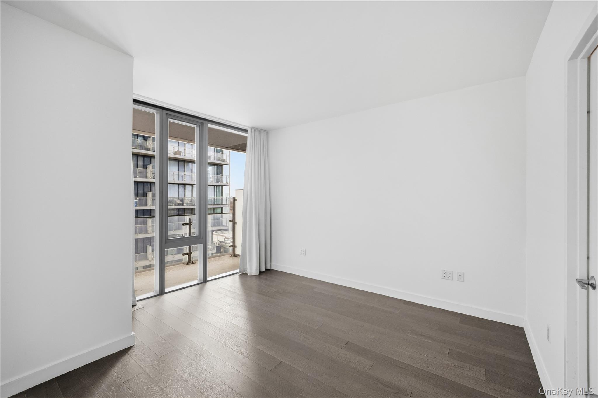 131-03 40 Road, Unit 11Q Queens, NY 11354 - Photo 11 of 31 an empty room with wooden floor and cabinet