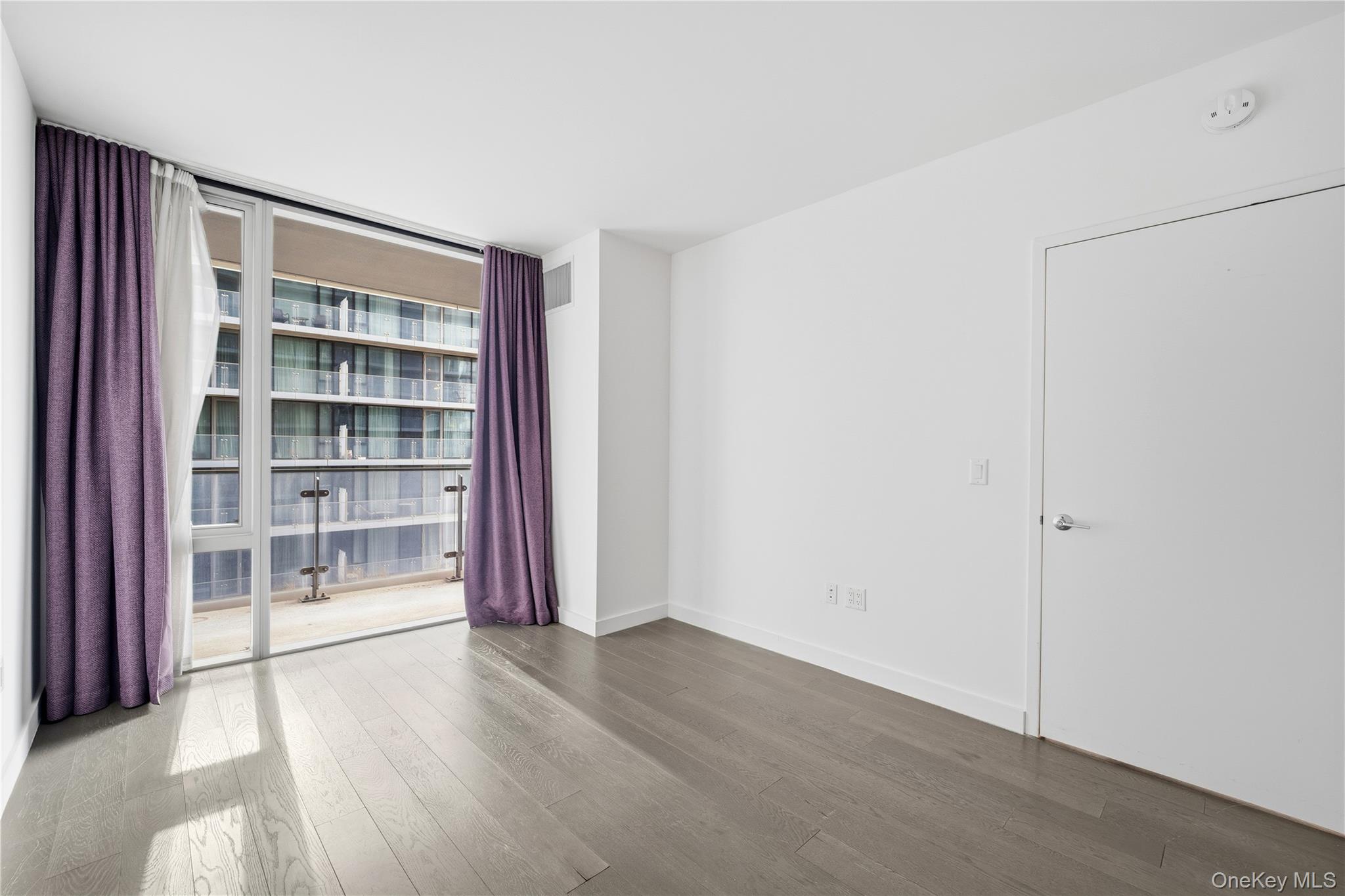 131-03 40 Road, Unit 11Q Queens, NY 11354 - Photo 9 of 31 a view of an empty room with a window and wooden floor