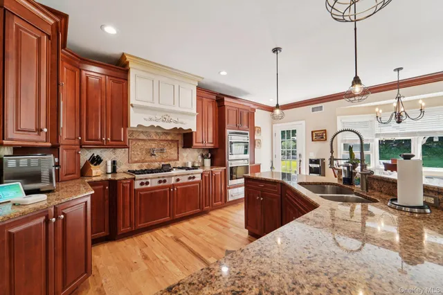 a large kitchen with stainless steel appliances granite countertop a stove a sink dishwasher and cabinets with wooden floor