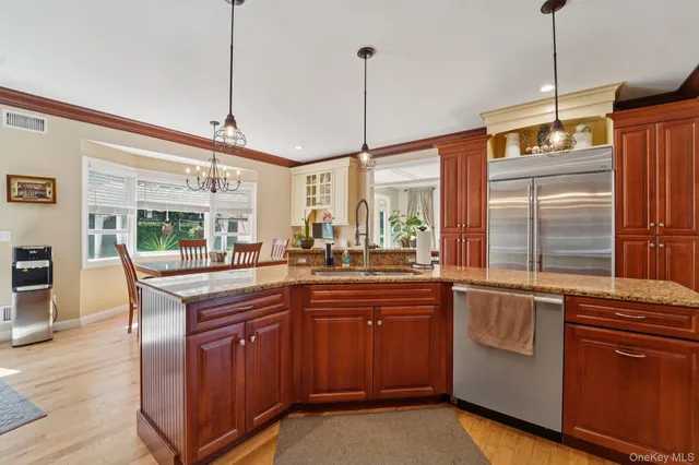 a kitchen with granite countertop stainless steel appliances a sink a counter space and a wooden floor