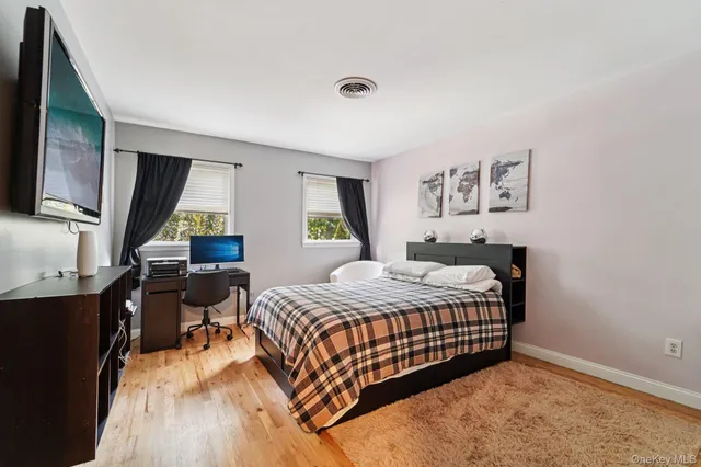 a bedroom with a bed and dresser with wooden floor