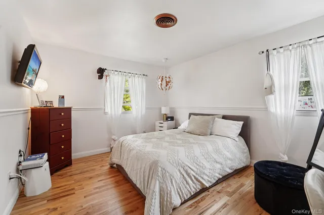 a bedroom with a bed and a flat tv screen on dresser
