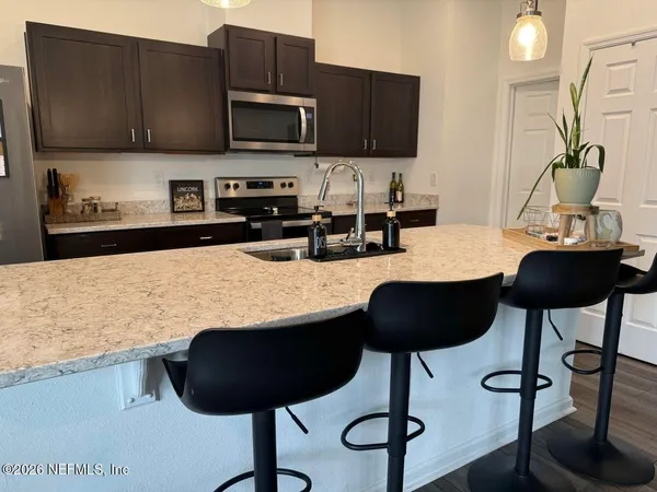 a kitchen with granite countertop a stove a sink and a microwave