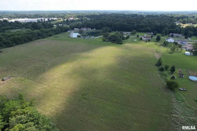an aerial view of a houses with outdoor space and trees all around