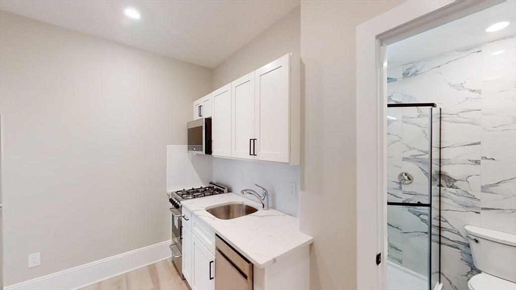 41 Edgerly Road, Unit 26 Boston, MA 02115 - Photo 5 of 9 a bathroom with a sink and a washer dryer