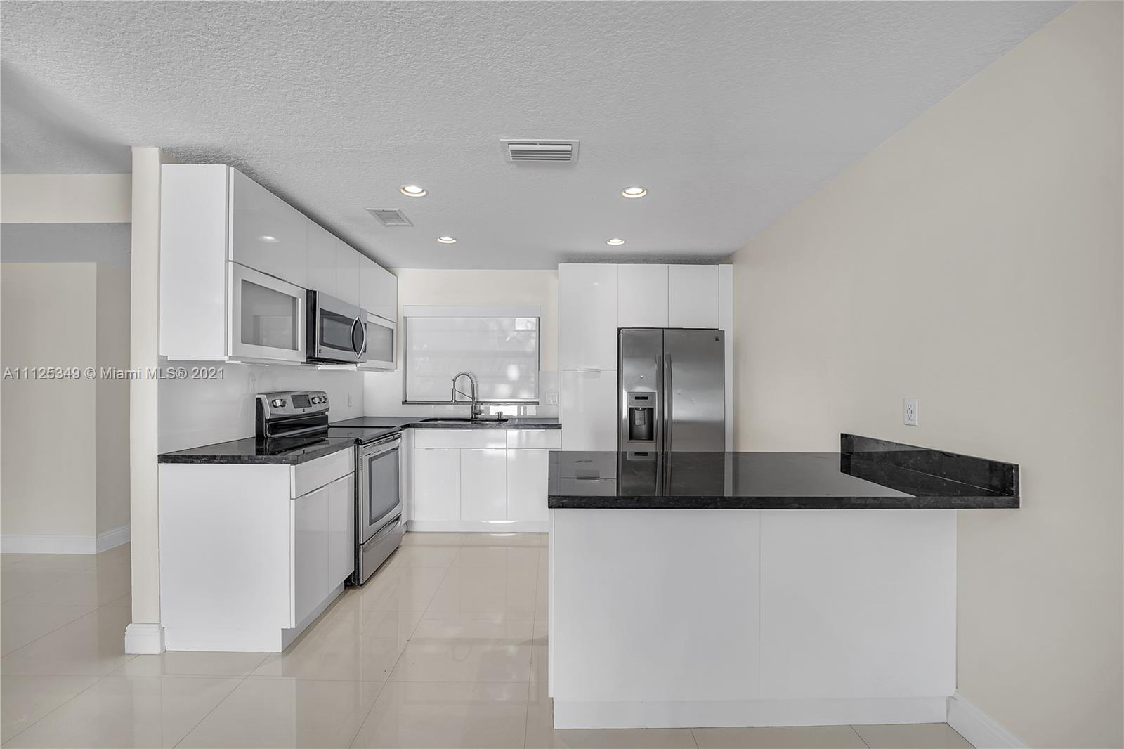 The Crossings Miami, FL 33186 - Photo 13 of 31 a large white kitchen with stainless steel appliances granite countertop a stove a sink a refrigerator and white cabinets