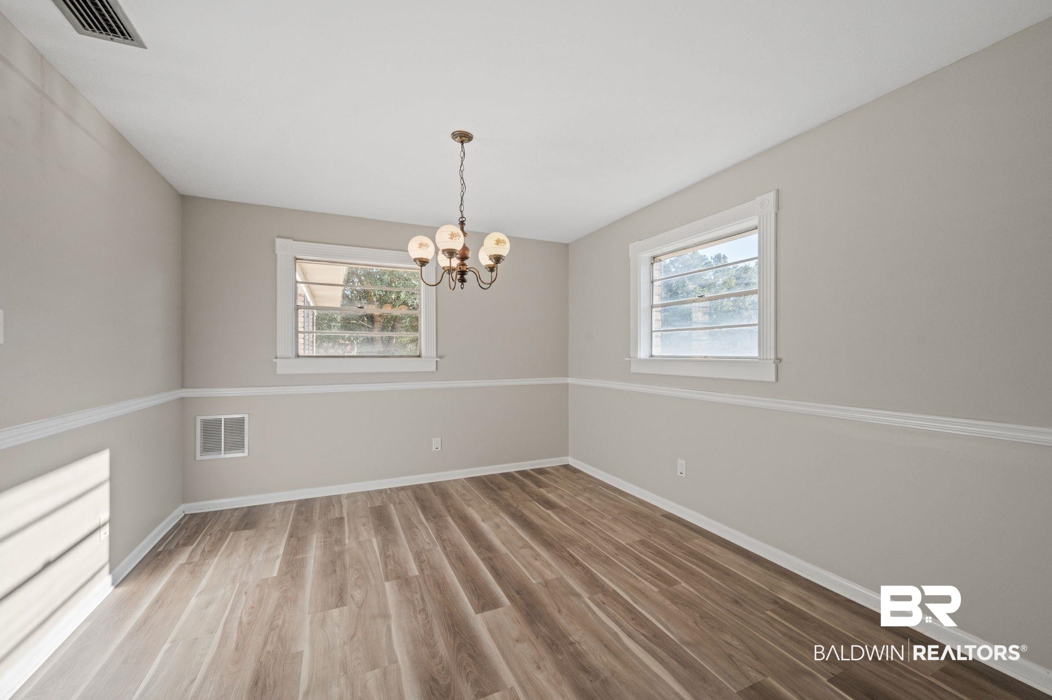 909 Caroline Avenue Daphne, AL 36526 - Photo 16 of 46 Spare room featuring hardwood / wood-style floors and a notable chandelier