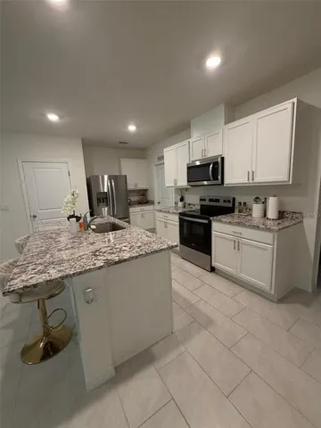 a kitchen with kitchen island granite countertop a stove sink and cabinets
