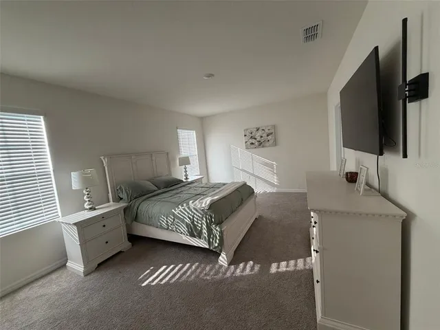a spacious bedroom with a bed and a flat screen tv