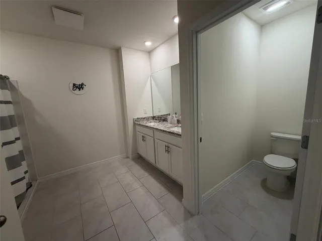 a bathroom with a granite countertop sink a toilet and a mirror