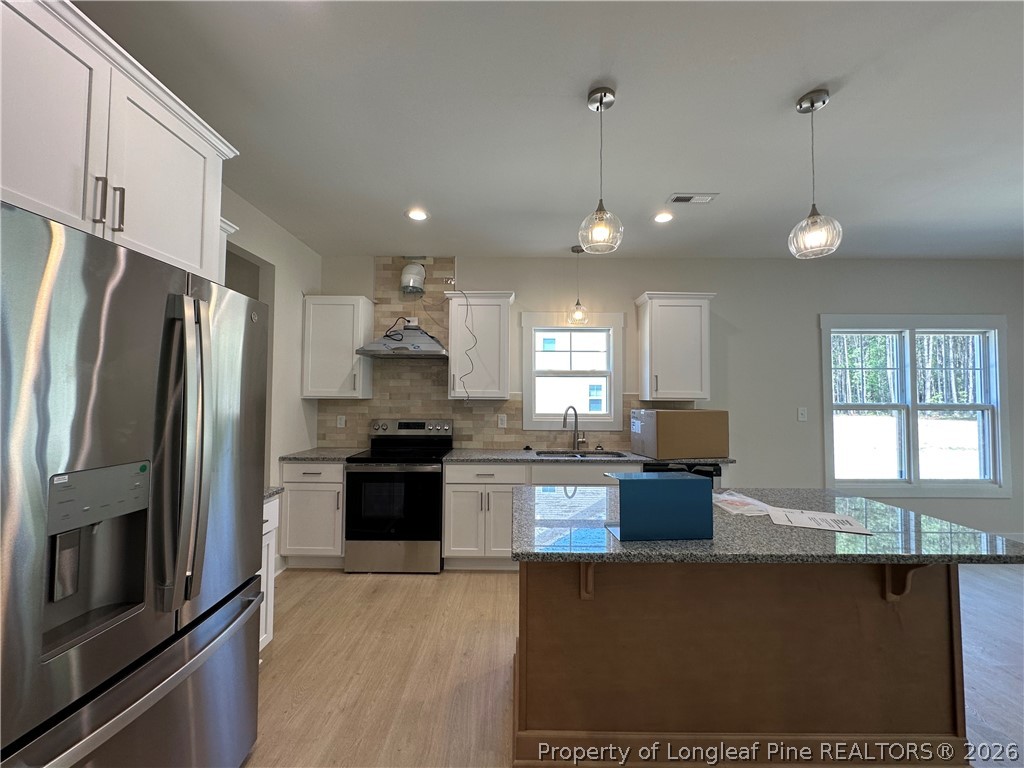 2908 Calloway Road Raeford, NC 28376 - Photo 9 of 25 a kitchen with stainless steel appliances granite countertop a refrigerator a sink dishwasher a stove and white cabinets with wooden floor