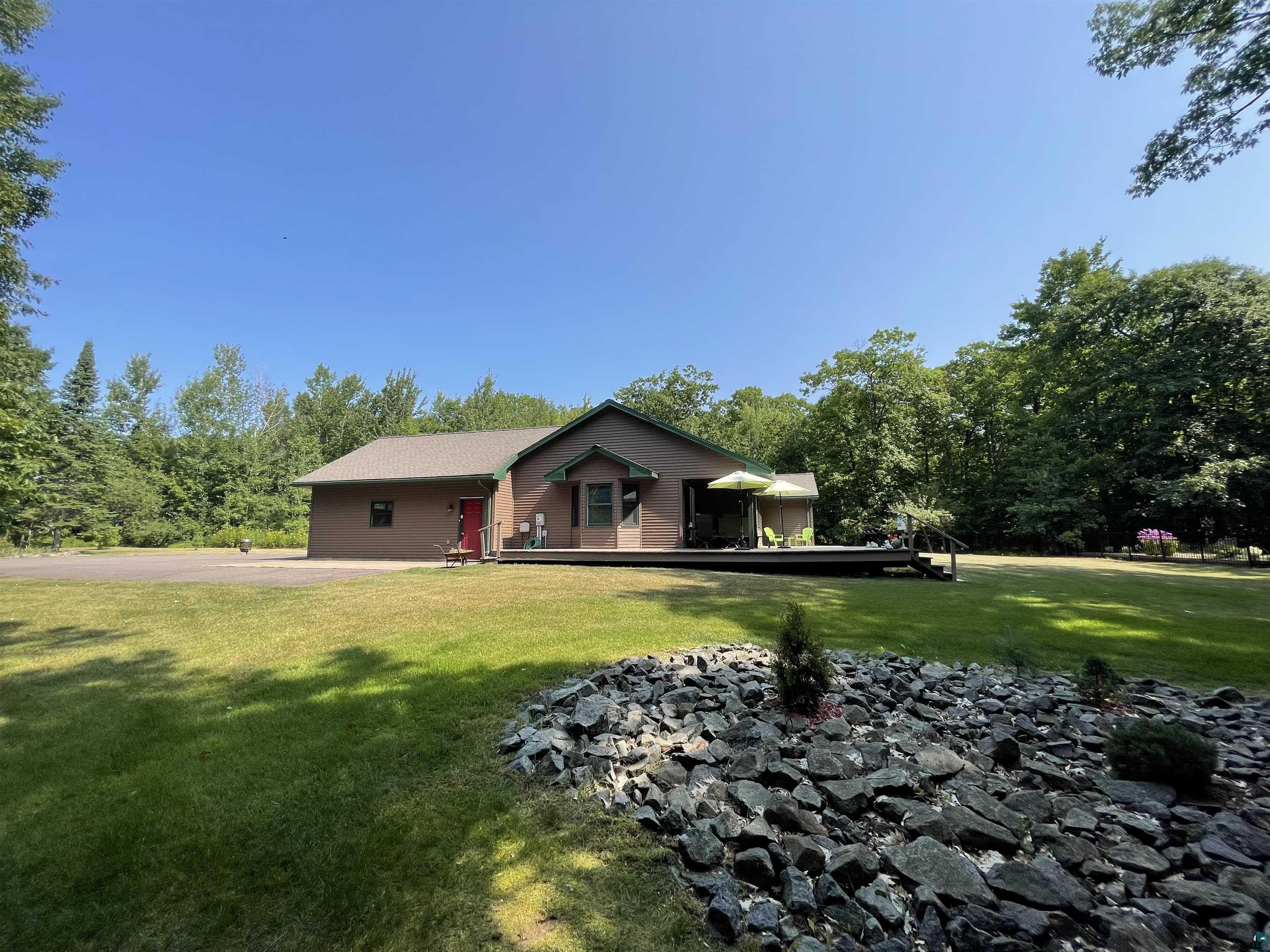 84830 Old San Road Bayfield, WI 54814 - Photo 18 of 30 Spacious exterior with vinyl siding, expansive deck, and a large grassy yard featuring a rock garden and a fenced in flower garden.