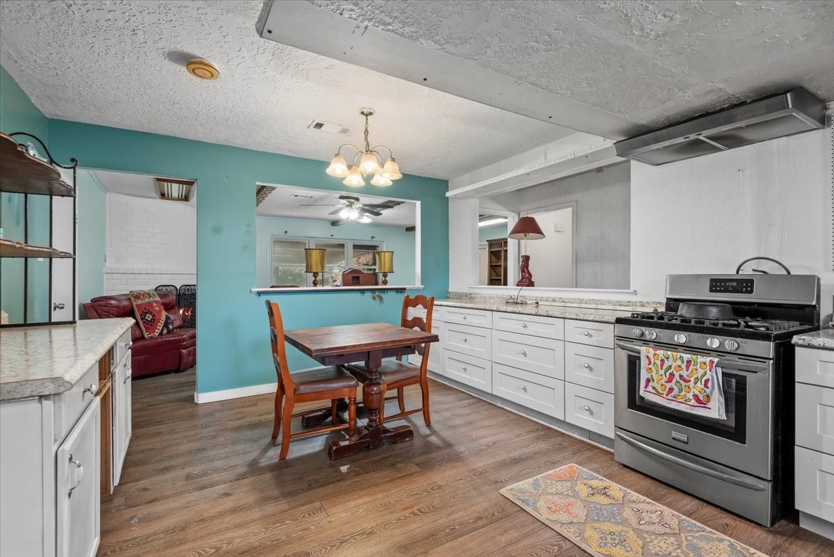 504 Catfish Lane Conroe, TX 77384 - Photo 14 of 48 a kitchen with stainless steel appliances granite countertop a stove a sink dishwasher a dining table and chairs with wooden floor