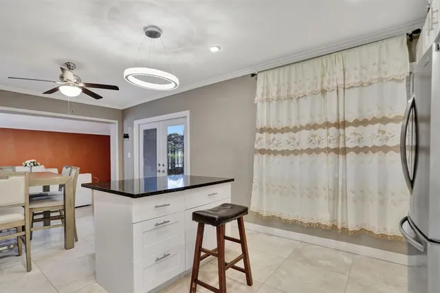 a kitchen with stainless steel appliances granite countertop a stove a refrigerator a sink and white cabinets with wooden floor