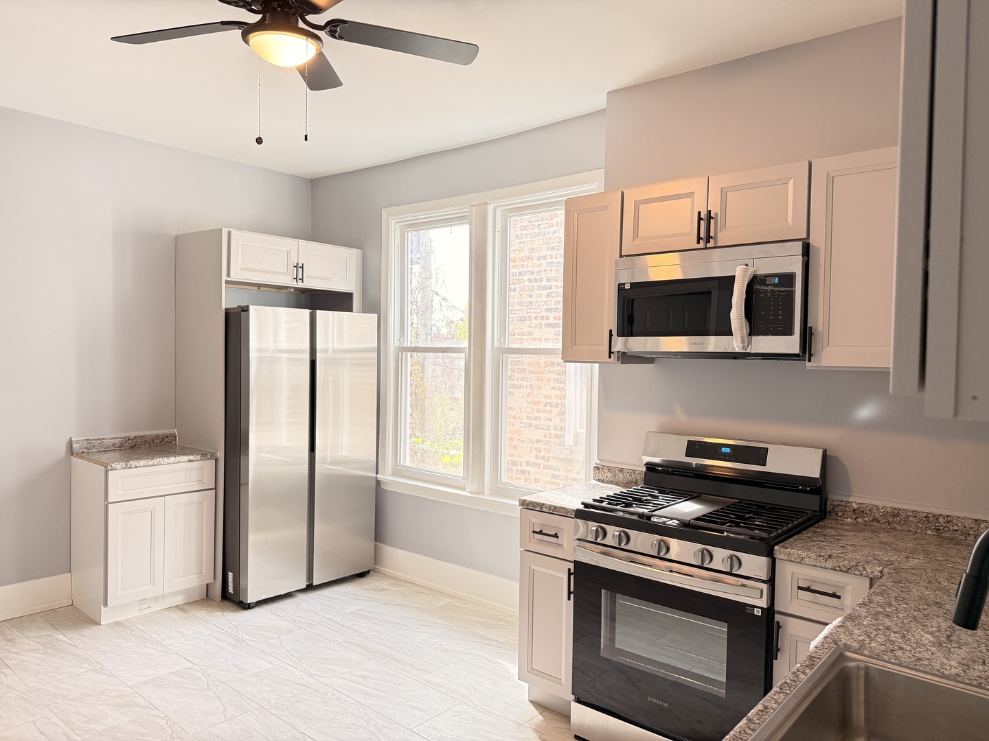 3821 West Fillmore Street, Unit 2R Chicago, IL 60624 - Photo 4 of 12 a kitchen with stainless steel appliances granite countertop a stove a refrigerator and a microwave