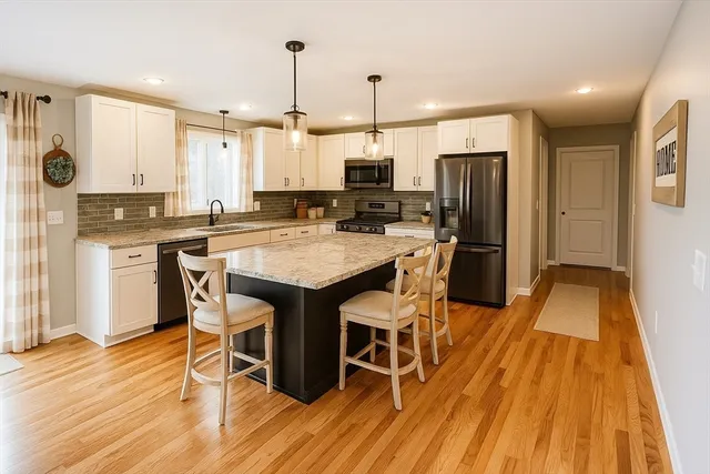 a kitchen with stainless steel appliances a dining table chairs stove refrigerator and cabinets