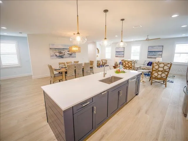 a large kitchen with kitchen island a large island a sink a stove and wooden floor