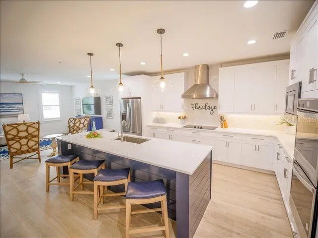 a kitchen with stainless steel appliances kitchen island granite countertop a table chairs and a refrigerator
