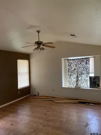 an empty room with wooden floor and windows