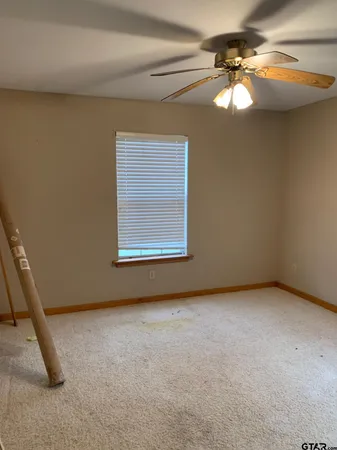an empty room with a chandelier fan and windows