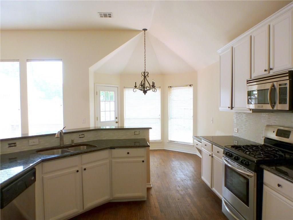 9911 Max Lane Frisco, TX 75035 - Photo 10 of 16 a kitchen with granite countertop stainless steel appliances a sink cabinets and wooden floor