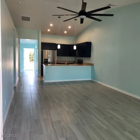 an empty room with wooden floor and a ceiling fan