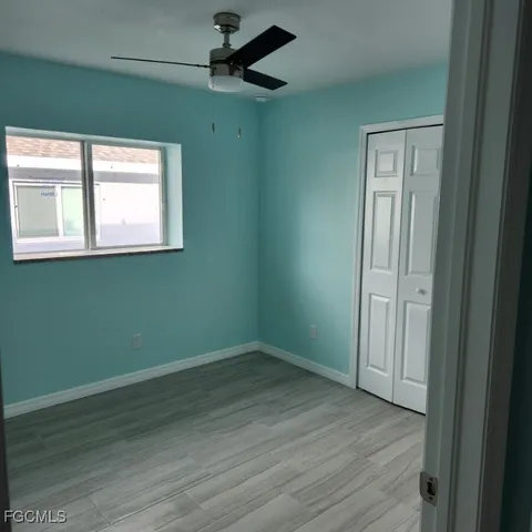 an empty room with wooden floor cabinet and windows
