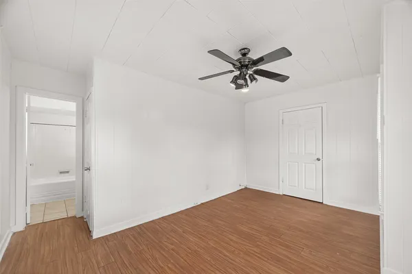 a view of a big room with wooden floor and a chandelier fan