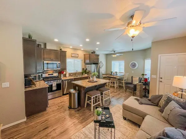 a living room with lots of furniture kitchen view and a wooden floor
