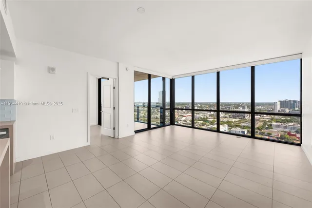 a view of an empty room with chandelier fan and windows