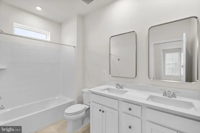 a bathroom with a double vanity sink toilet mirror and bathtub