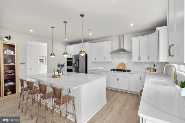 a kitchen with stainless steel appliances kitchen island granite countertop a stove a sink a refrigerator and white cabinets with wooden floor