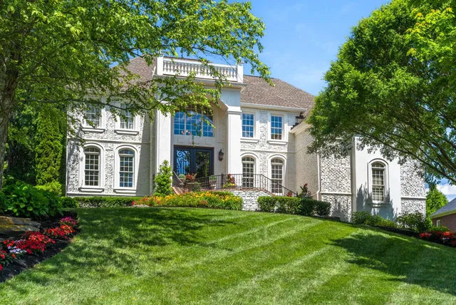 a front view of a house with garden and trees