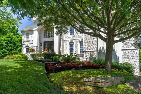 a front view of a house with garden and trees