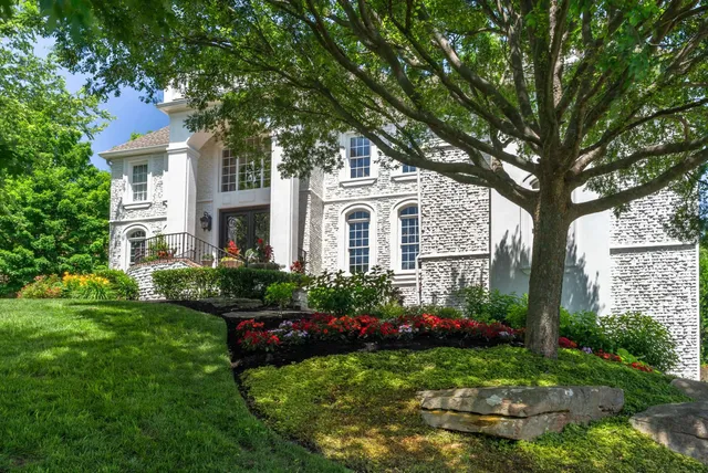 a front view of a house with garden and trees