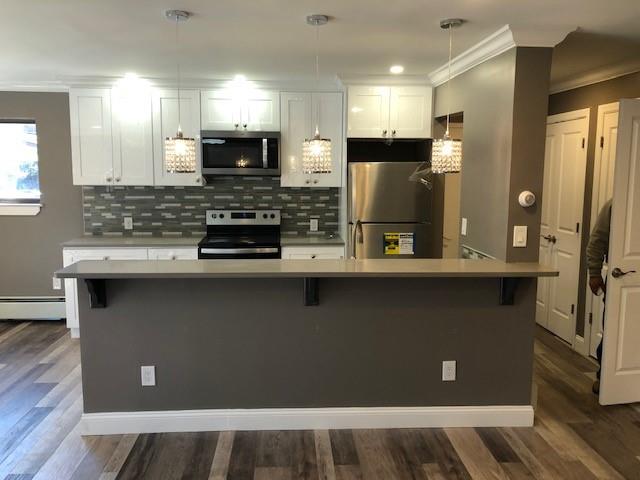 a kitchen with kitchen island granite countertop a refrigerator and a stove top oven