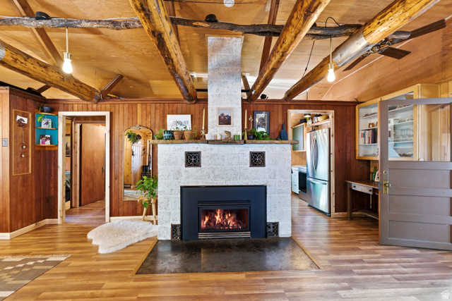 6631 Pine Springs Road Kamas, UT 84036 - Photo 20 of 48 Detailed view of beam ceiling, wooden walls, freestanding refrigerator, wood finished floors, and a tiled fireplace